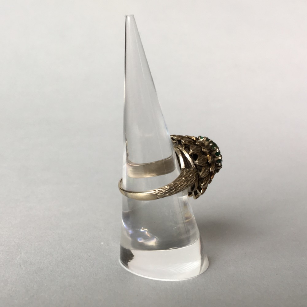 A textured yellow gold cocktail ring featuring a central cluster of round brilliant diamonds surrounded by emeralds and feathered metalwork. View II