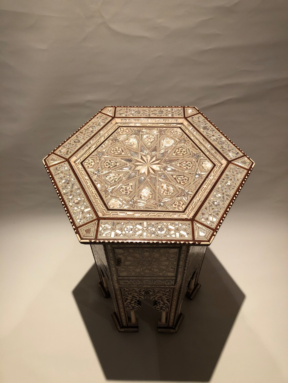 An octagonal dark wood side table with intricate bone and mother-of-pearl geometric inlay, featuring carved horseshoe arches and turned legs at the base. View II