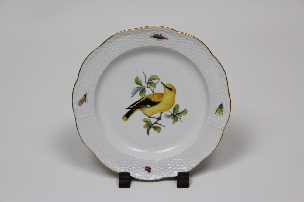 A set of three white circular porcelain plates featuring hand-painted birds perched on branches with small insect details, basketweave embossed borders, and gilded rims. View III