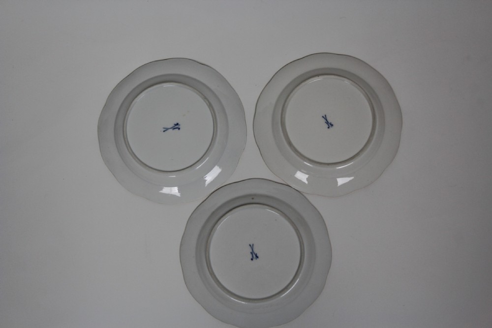 A set of three white circular porcelain plates featuring hand-painted birds perched on branches with small insect details, basketweave embossed borders, and gilded rims. View VI