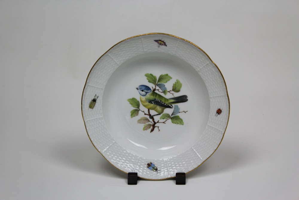 A set of three circular white porcelain dessert dishes featuring hand-painted birds and insects with basketweave moulded rims and gilt borders. View II