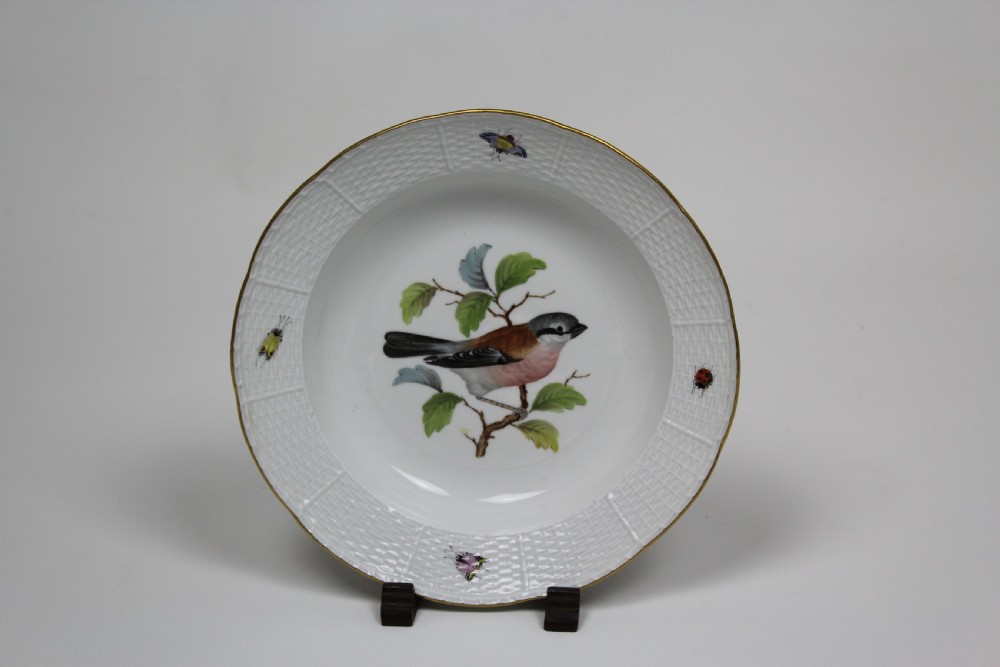 A set of three circular white porcelain dessert dishes featuring hand-painted birds and insects with basketweave moulded rims and gilt borders. View III
