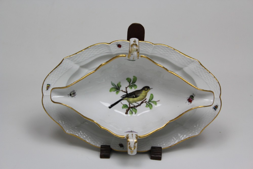 A white porcelain double-spouted sauce boat decorated with hand-painted bird and insect motifs, featuring gilded scalloped rims and an attached basketweave-moulded tray.