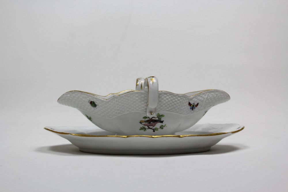 A white porcelain double-spouted sauce boat decorated with hand-painted bird and insect motifs, featuring gilded scalloped rims and an attached basketweave-moulded tray. View III