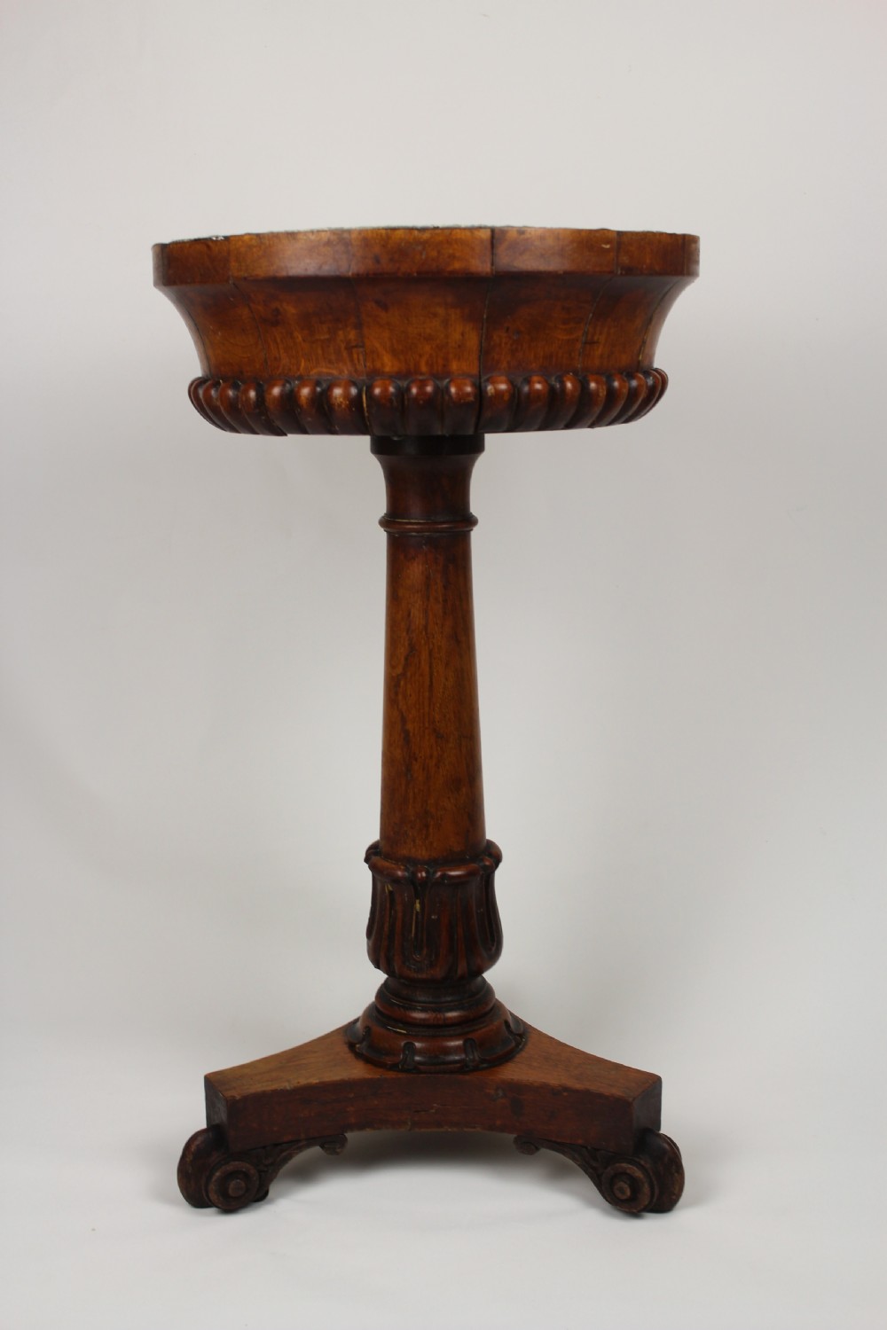 A golden oak jardiniere stand featuring a carved circular basin, a turned central column, and a triform base with scroll feet. View II