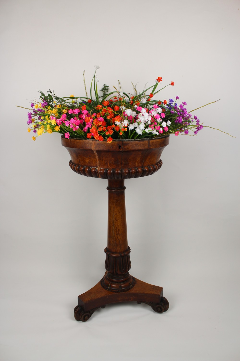 A golden oak jardiniere stand featuring a carved circular basin, a turned central column, and a triform base with scroll feet. View IV