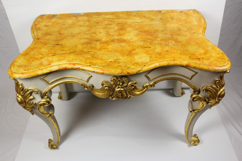 A French Louis XV style console table featuring a serpentine yellow sienna marble top over a grey painted frame decorated with giltwood acanthus carvings.