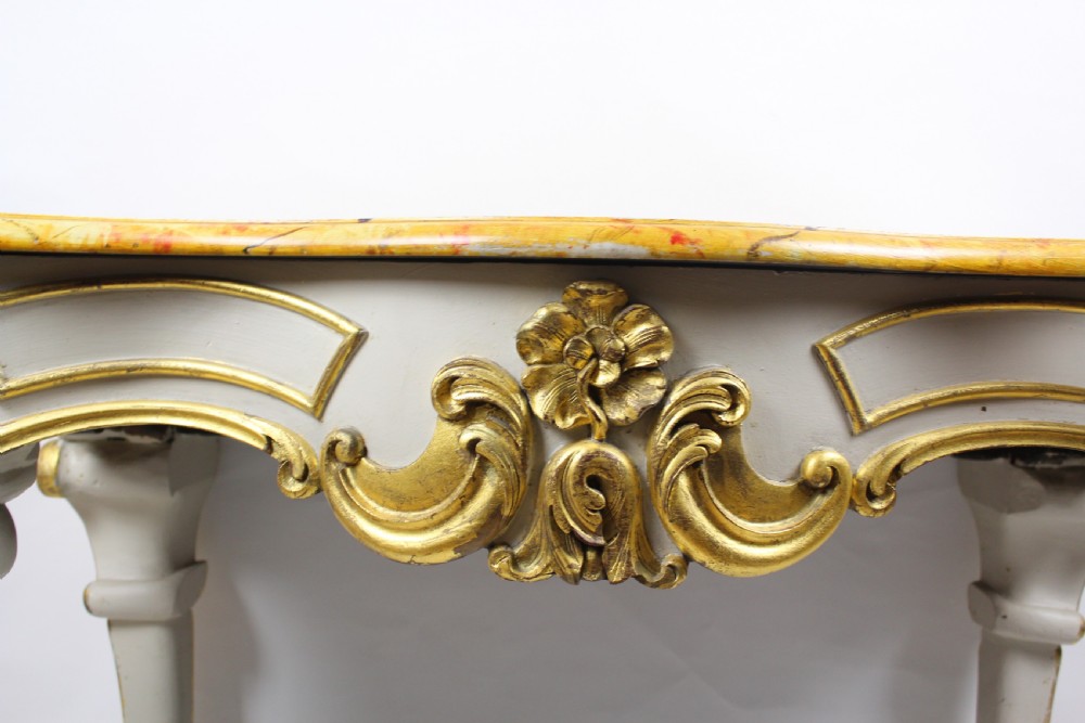 A French Louis XV style console table featuring a serpentine yellow sienna marble top over a grey painted frame decorated with giltwood acanthus carvings. View V
