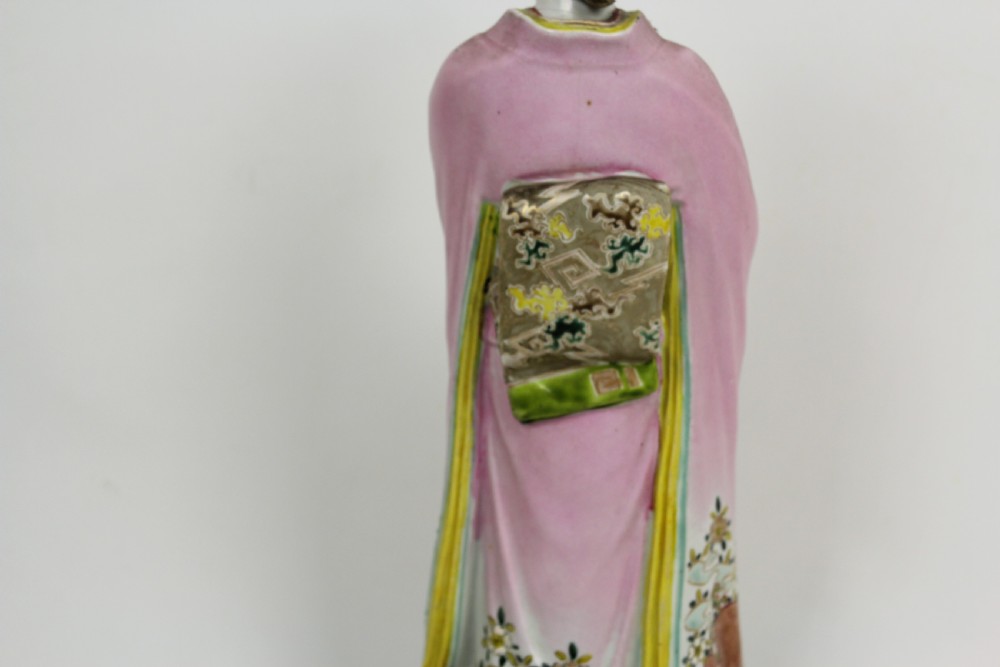 A hand-painted porcelain figurine of a Japanese geisha wearing a pink floral kimono with hand resting near her chin. View V