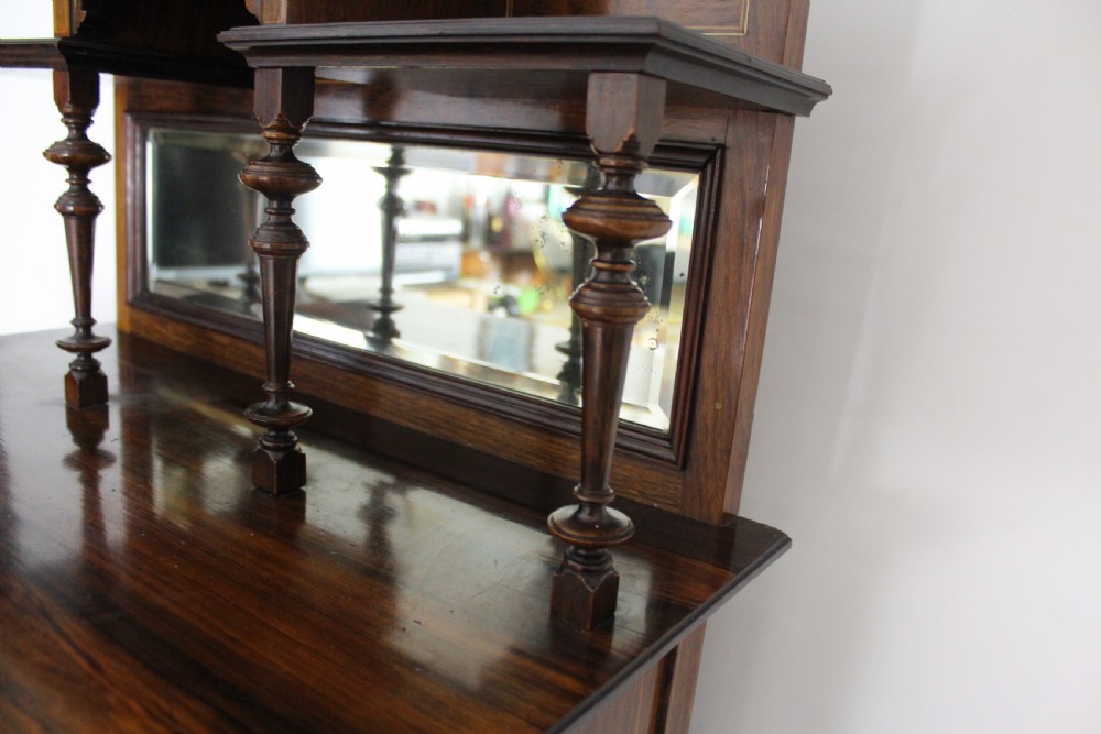 A Victorian inlaid rosewood music cabinet featuring a mirrored superstructure with turned spindles, a single glazed door with central marquetry motif, and an open lower shelf. View II