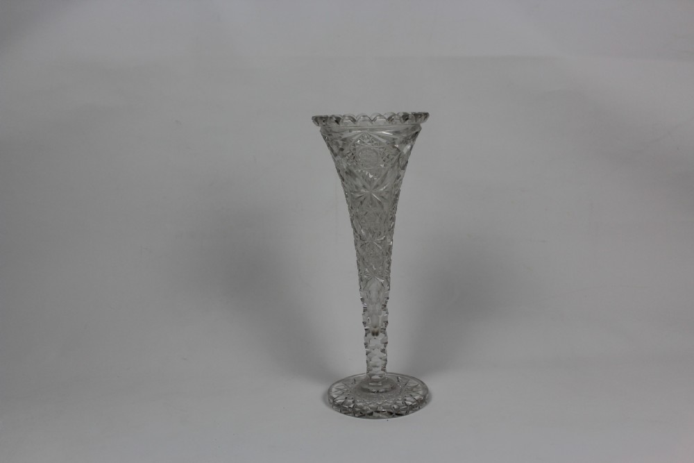 A tall trumpet-shaped clear hand-cut crystal vase featuring diamond cuts, a scalloped top rim, and a circular starburst pattern base. View II
