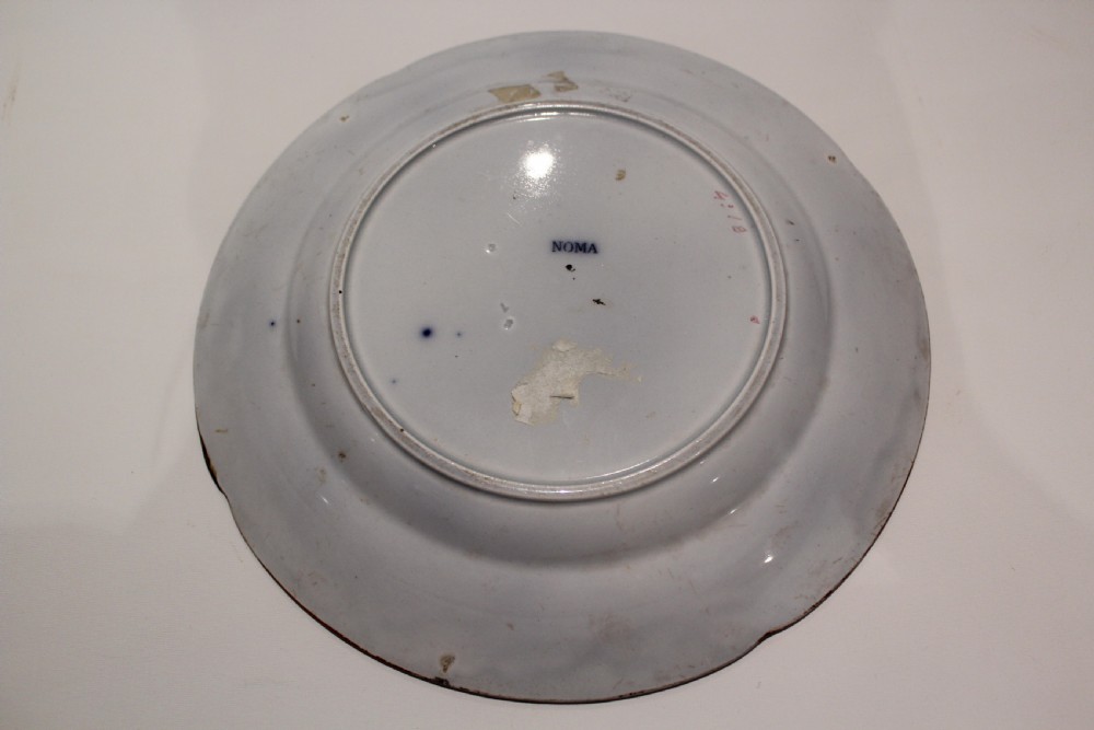 A circular Victorian ceramic plate featuring a central motif of a vase with flowers surrounded by a floral rim on a white glazed surface. View II