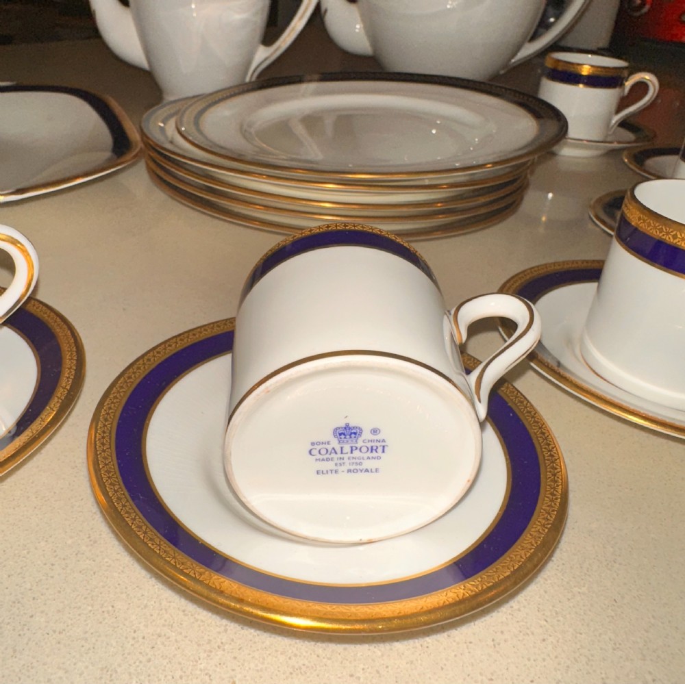 An antique white porcelain coffee service featuring cobalt blue borders and gold gilding, including a teapot, coffee pot, demitasse cups, saucers, side plates, and a serving dish. View II