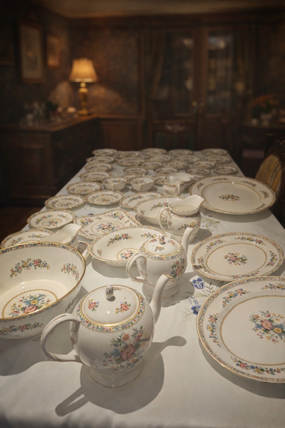 A Victorian Coalport porcelain dinner service featuring hand-painted botanical motifs and gilded rims displayed across a white cloth.