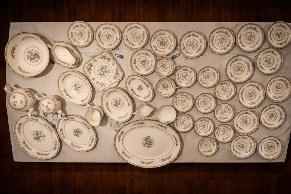 A Victorian Coalport porcelain dinner service featuring hand-painted botanical motifs and gilded rims displayed across a white cloth. View II