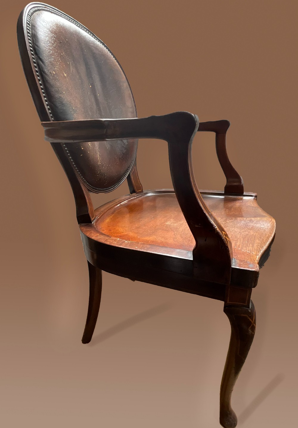 An English late nineteenth-century mahogany armchair featuring an upholstered dark leather oval backrest, curved armrests with inlay details, a shaped wooden seat, and cabriole legs. View III