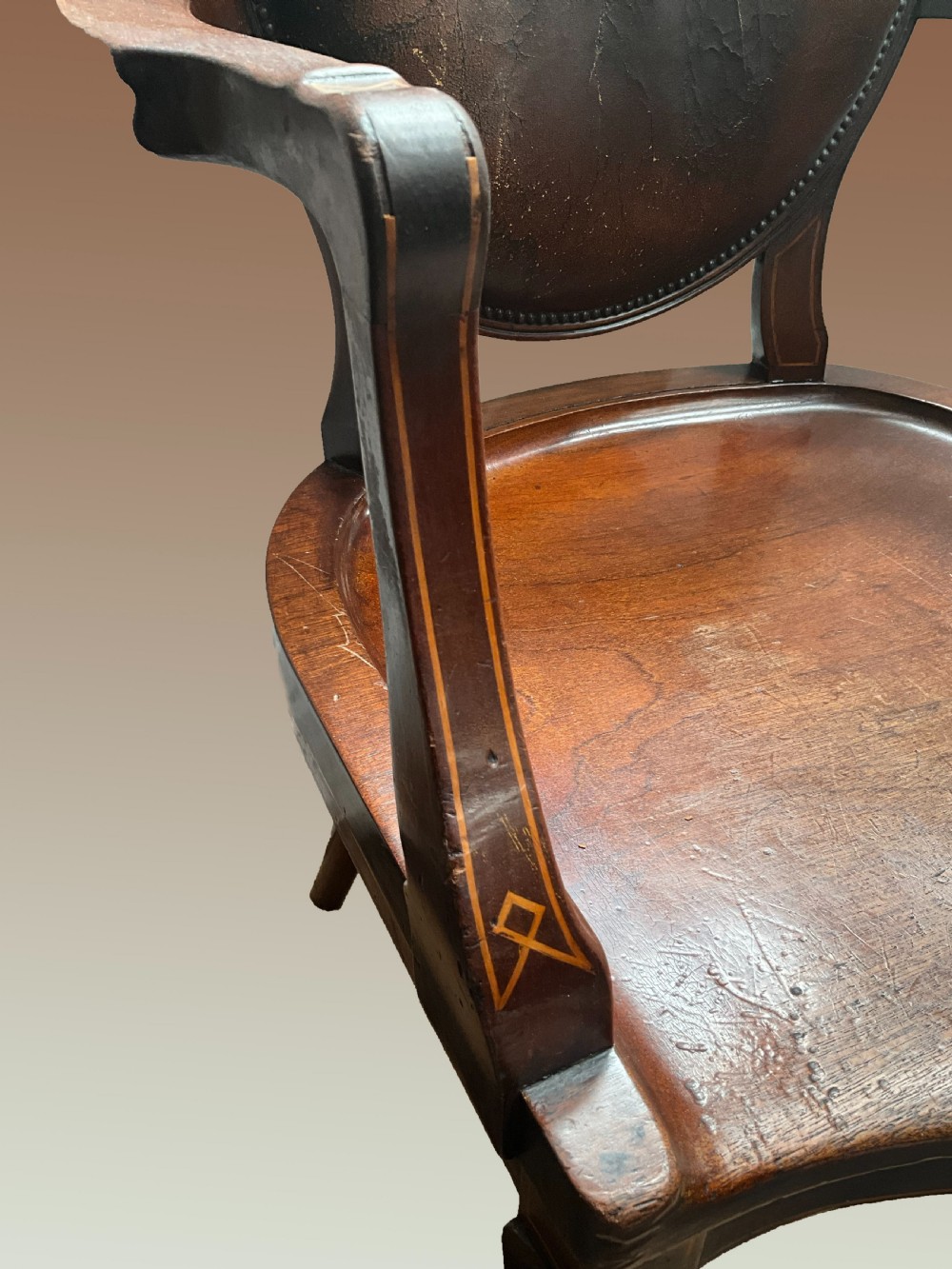 An English late nineteenth-century mahogany armchair featuring an upholstered dark leather oval backrest, curved armrests with inlay details, a shaped wooden seat, and cabriole legs. View IV