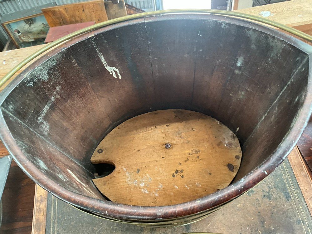 An early 19th-century elliptical mahogany bucket featuring horizontal brass banding, a brass swing handle, and a removable internal brass liner. View IV