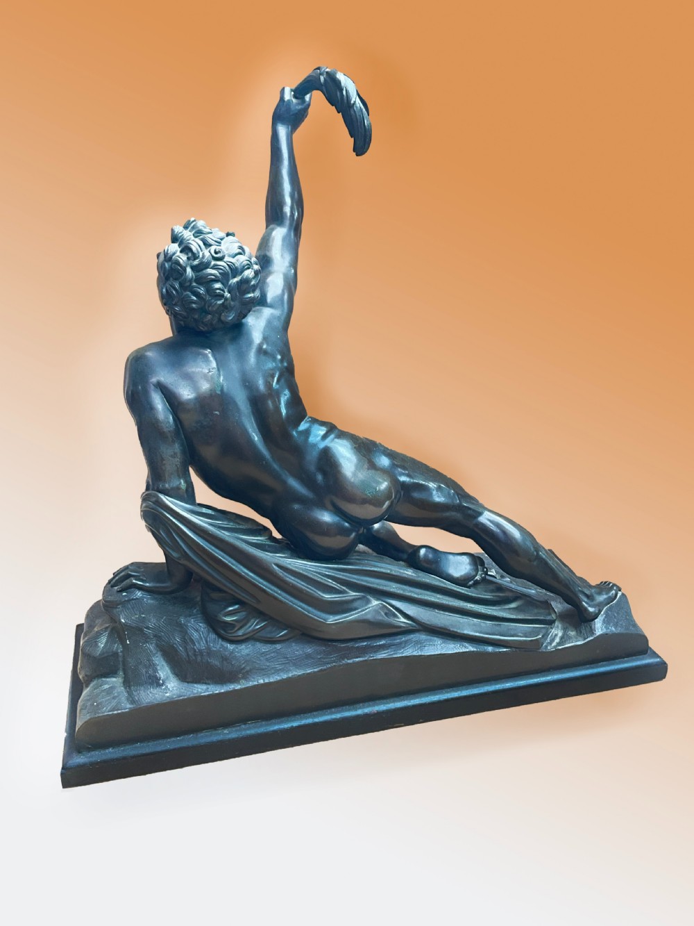 A patinated bronze sculpture depicting a semi-nude Classical soldier reclining on a rocky base with one arm raised aloft. View III