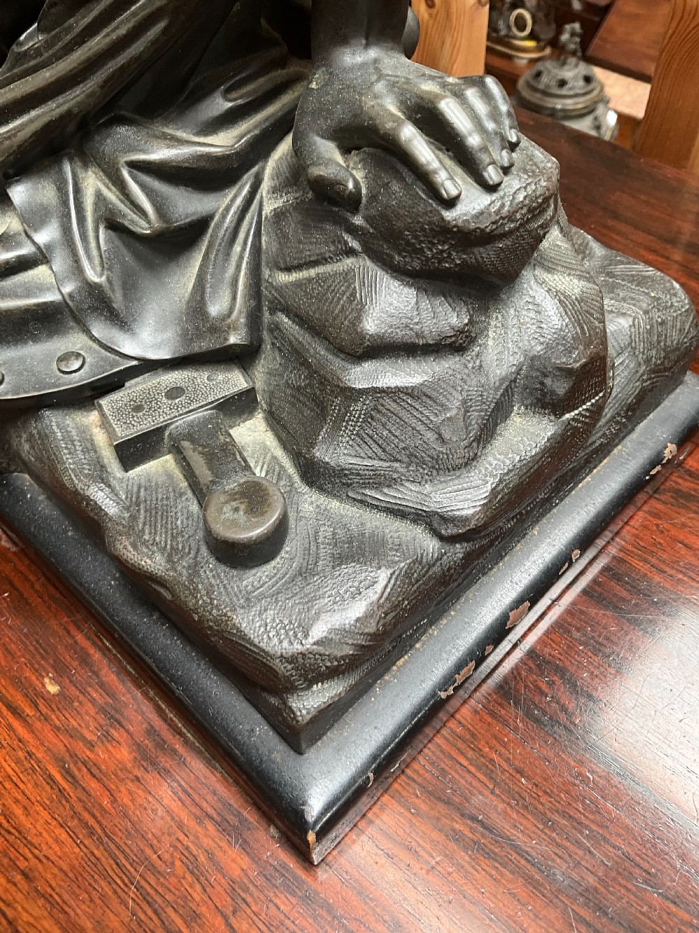 A patinated bronze sculpture depicting a semi-nude Classical soldier reclining on a rocky base with one arm raised aloft. View V