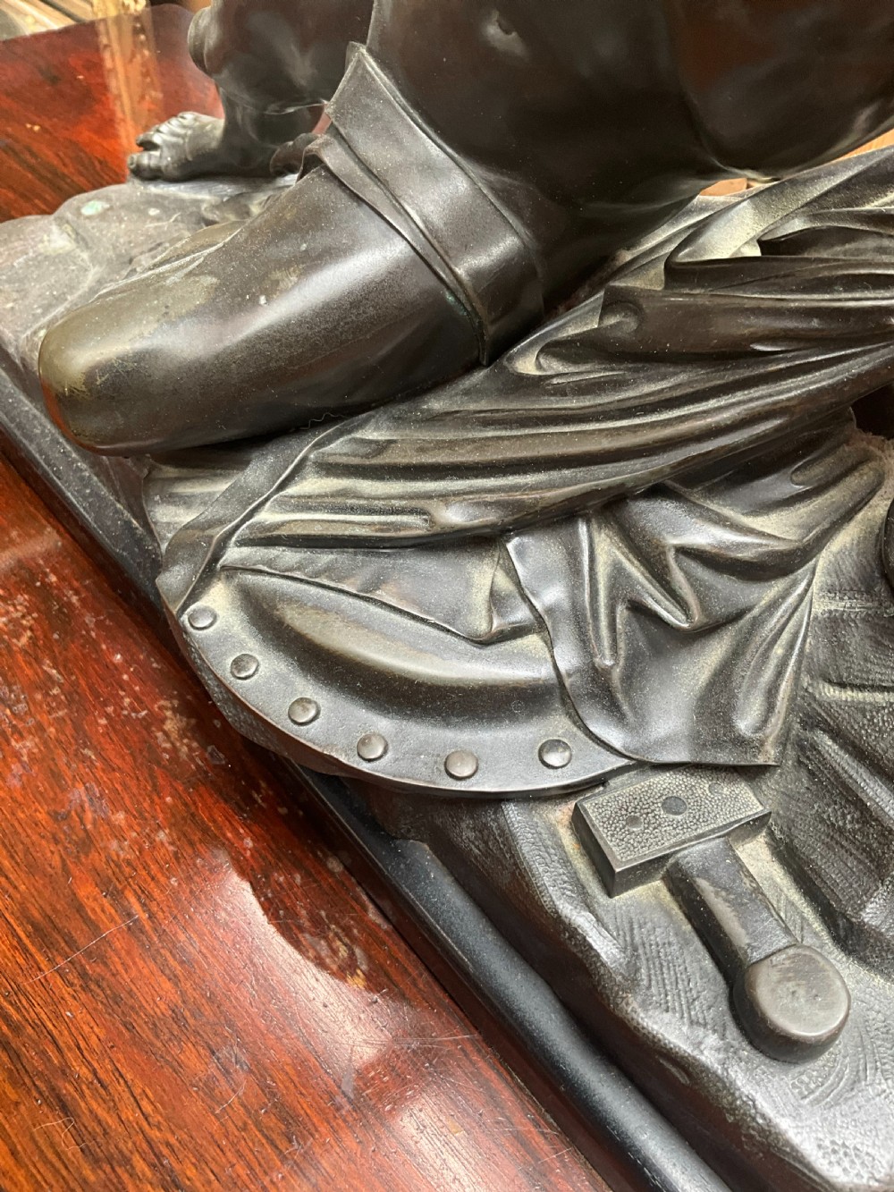 A patinated bronze sculpture depicting a semi-nude Classical soldier reclining on a rocky base with one arm raised aloft. View VI