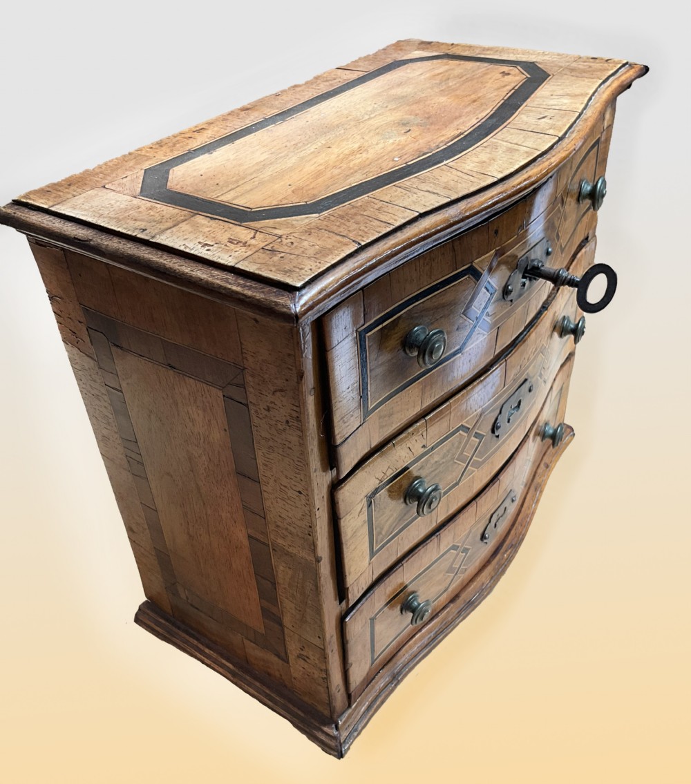 An early 19th century inlaid walnut serpentine fronted miniature chest of drawers View IV