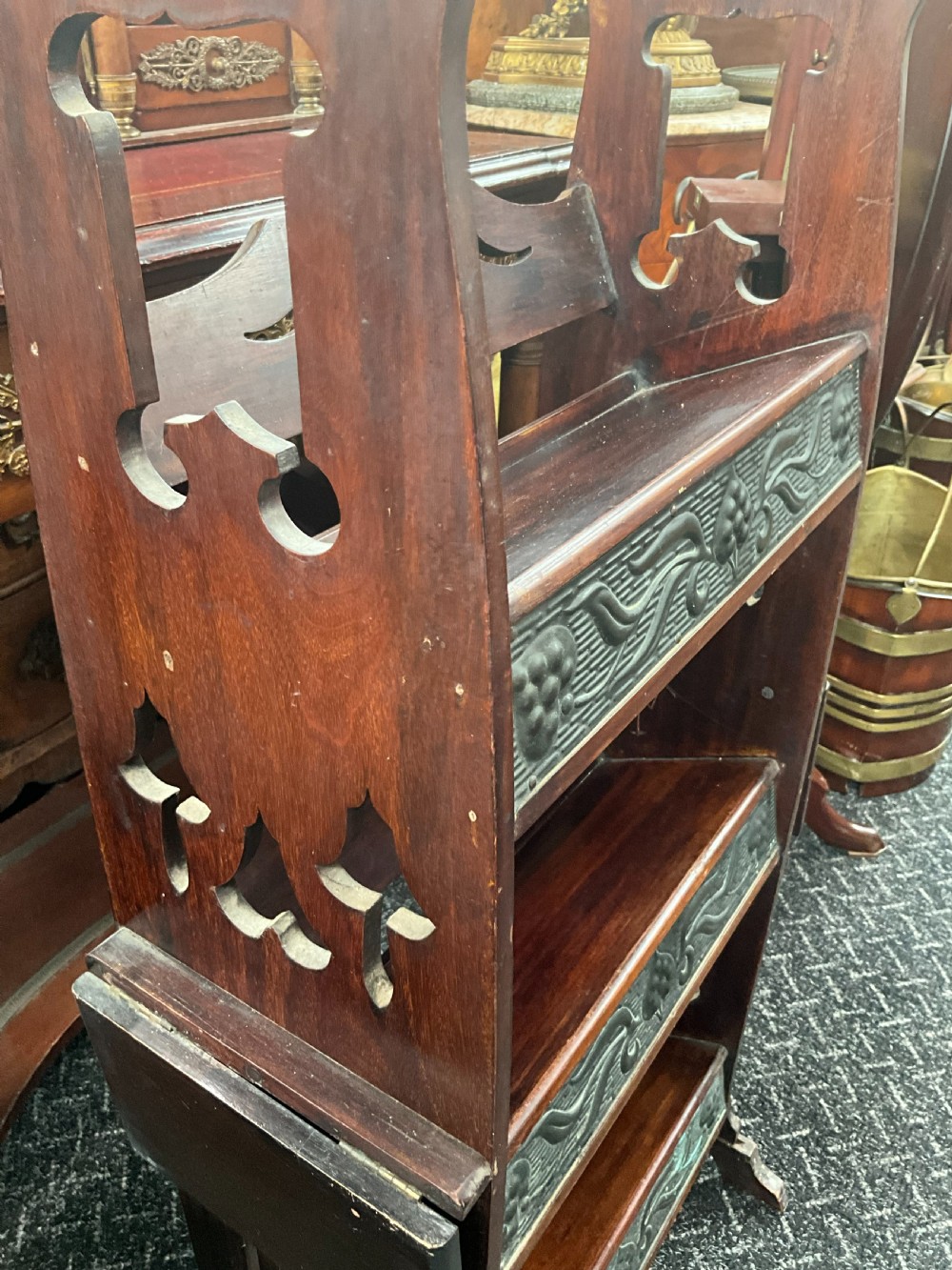 An Art Nouveau dark wood open bookcase featuring side drop-leaf shelves and decorative embossed metal panels with organic motifs. View III