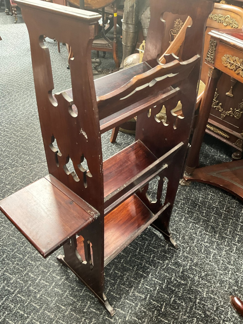 An Art Nouveau dark wood open bookcase featuring side drop-leaf shelves and decorative embossed metal panels with organic motifs. View V