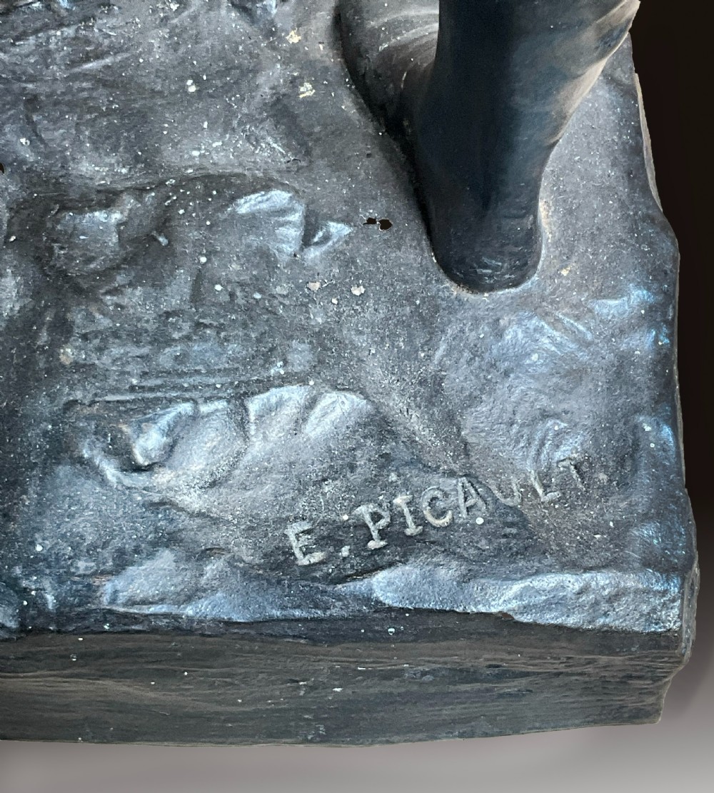 A dark patinated bronze statue of a soldier holding a long spear on a rocky base. View III