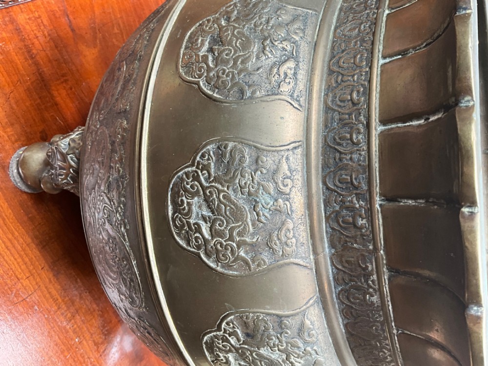 A pair of patinated bronze Oriental jardinieres featuring relief dragon carvings, scalloped rims, and tripod mask feet. View V