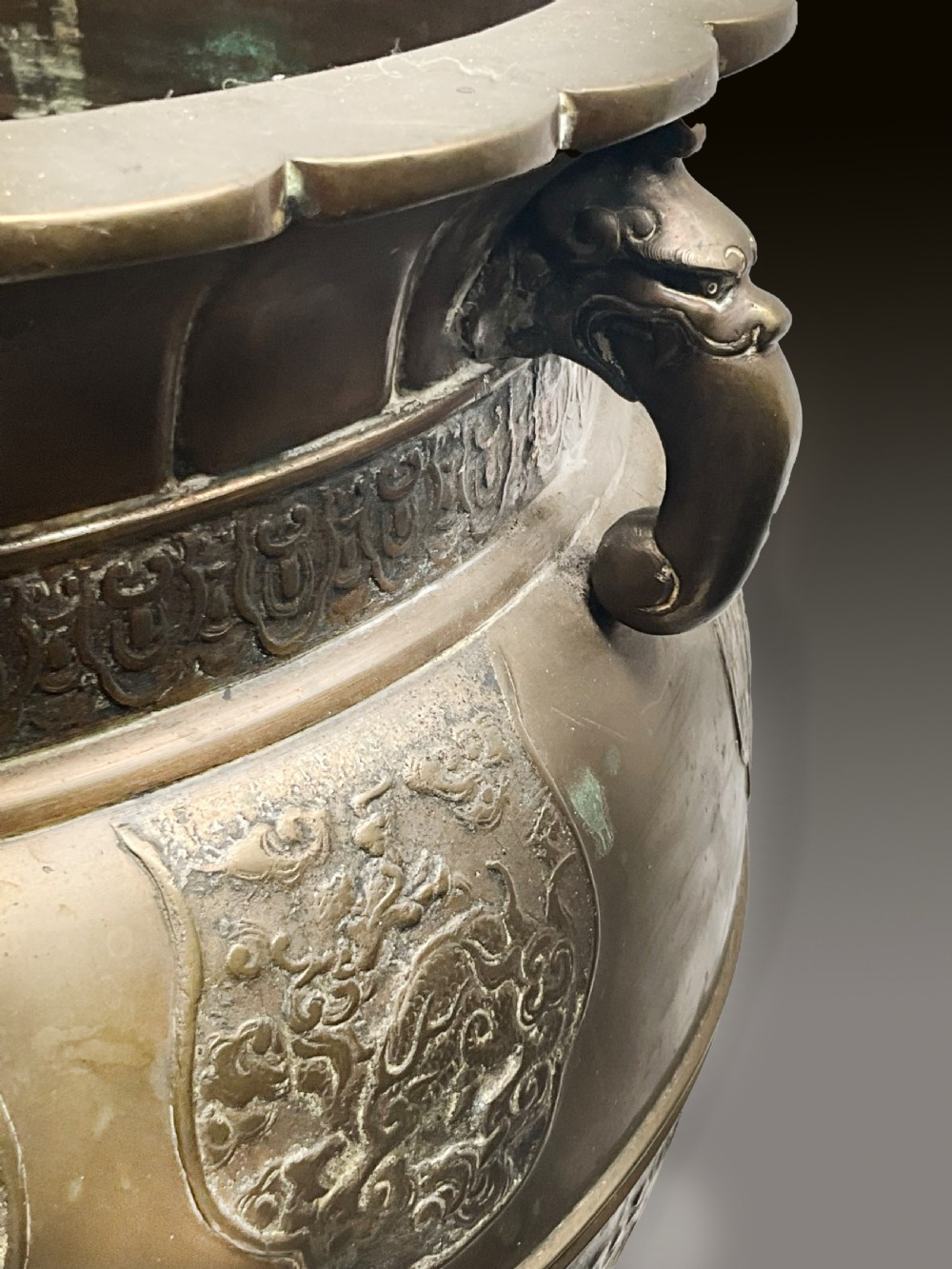 A pair of patinated bronze Oriental jardinieres featuring relief dragon carvings, scalloped rims, and tripod mask feet. View VI