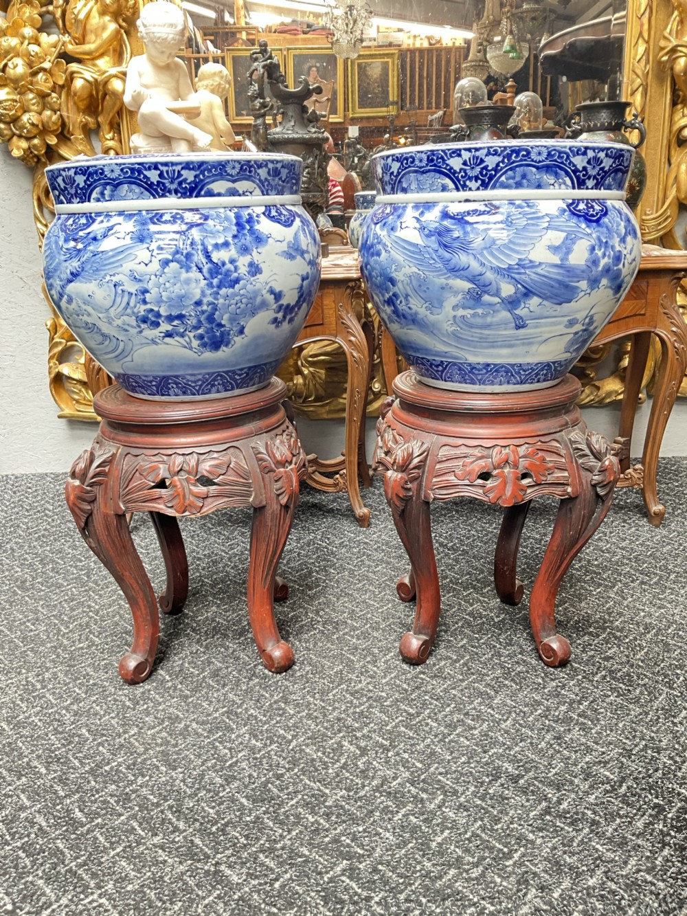 A pair of large round blue and white Japanese porcelain jardinieres decorated with avian motifs resting on intricately carved hardwood stands. View VIII