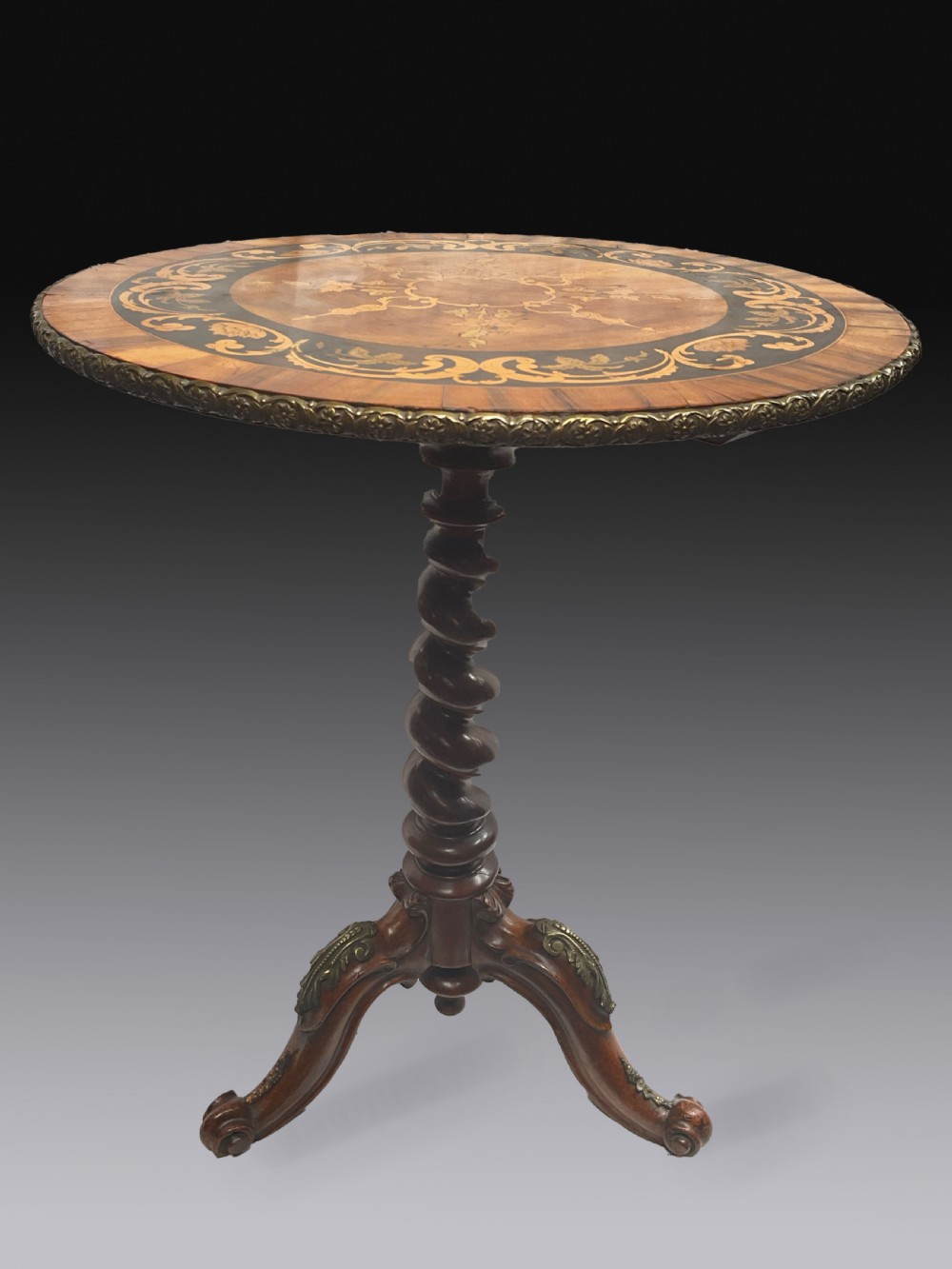 A Victorian circular walnut wine table featuring floral marquetry wood inlay on the top, a spiral-carved central column, and a tripod base with brass accents.