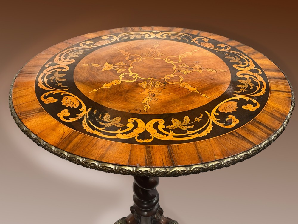 A Victorian circular walnut wine table featuring floral marquetry wood inlay on the top, a spiral-carved central column, and a tripod base with brass accents. View V