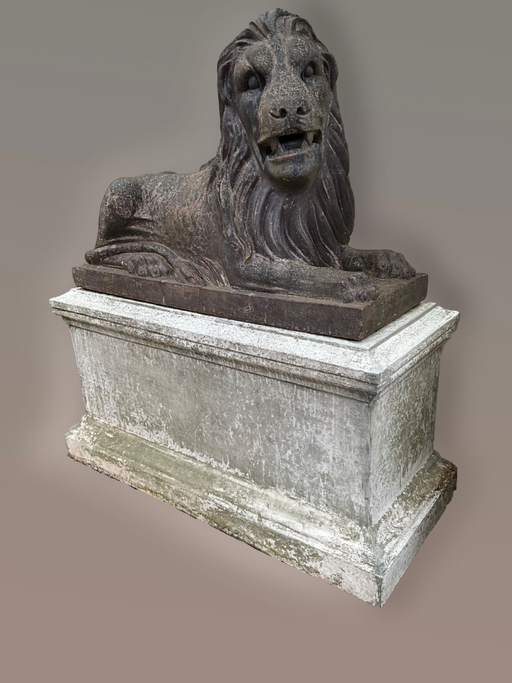 A pair of nineteenth-century salt-glazed stoneware recumbent lions resting on rectangular plinths with a distressed finish. View V
