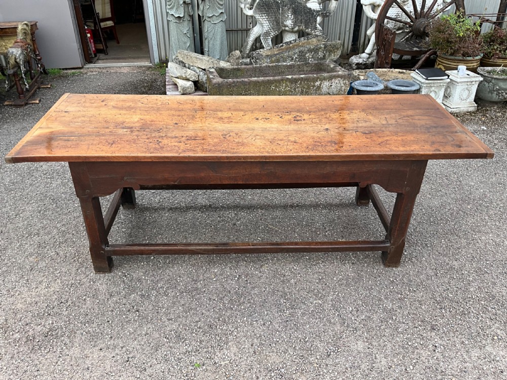 A long English oak refectory dining table featuring a three-plank top, breadboard ends, apron spandrels, and a low stretcher base. View IV