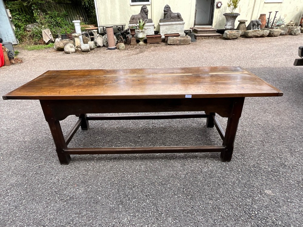 A long English oak refectory dining table featuring a three-plank top, breadboard ends, apron spandrels, and a low stretcher base. View X