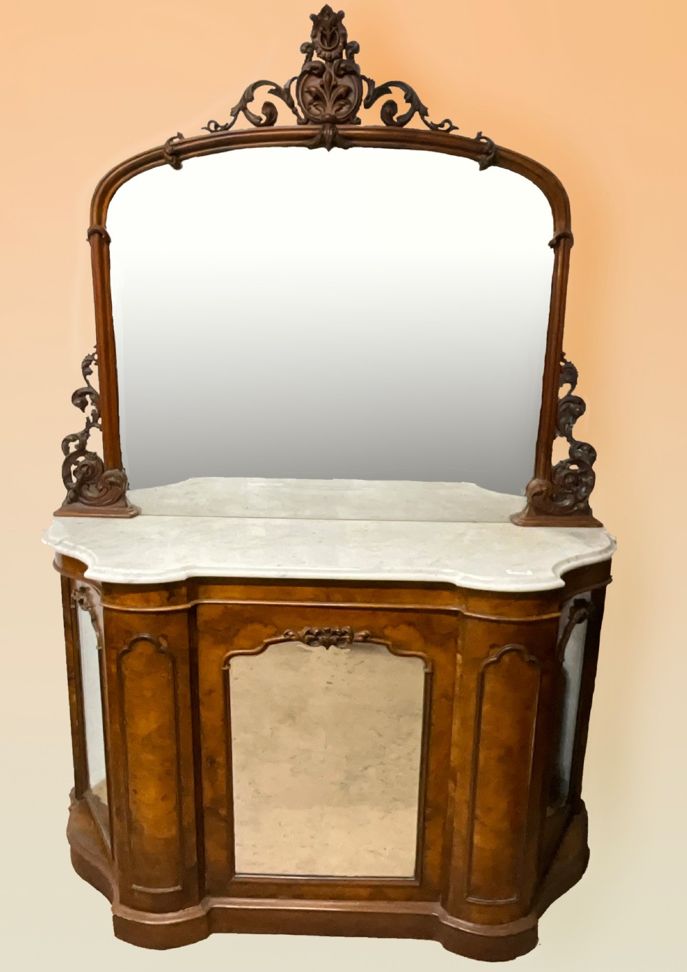 A 19th-century Victorian burr walnut credenza with a white marble top, mirrored front panels, and a carved arching mirror frame top.