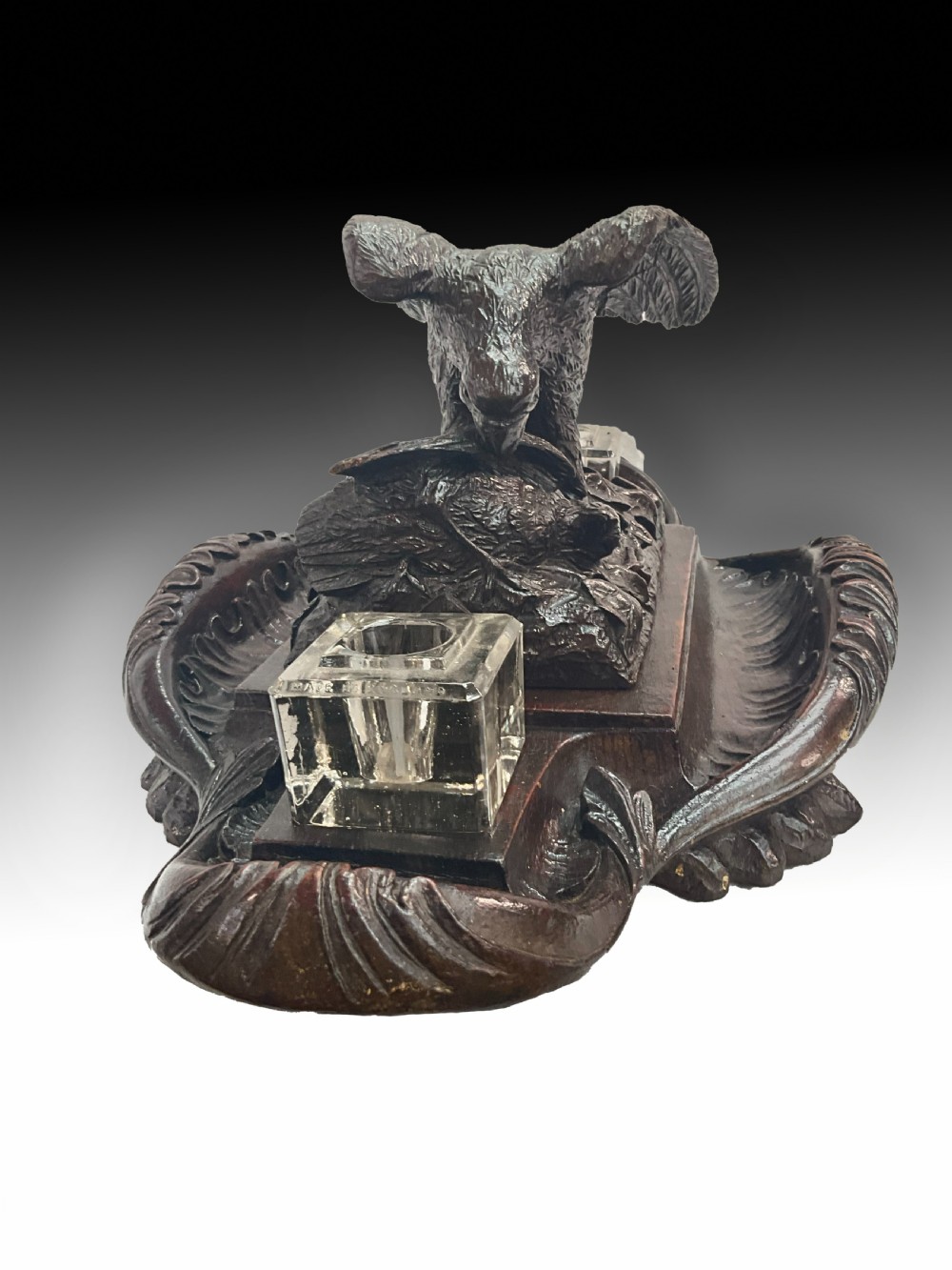 A carved dark wood Black Forest inkstand featuring a central eagle figure perched over prey, flanked by two square glass inkwells. View II