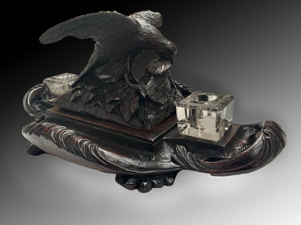 A carved dark wood Black Forest inkstand featuring a central eagle figure perched over prey, flanked by two square glass inkwells. View IV
