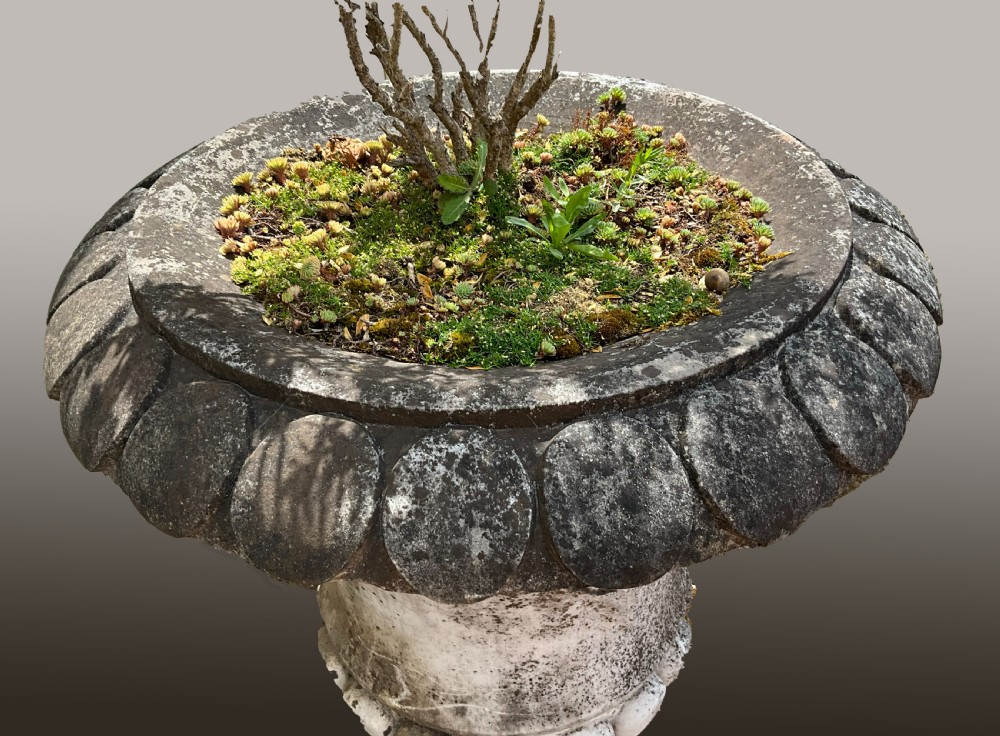A near pair of large carved marble garden urns with weathered grey surfaces, gadrooned rims, and lobed bases. View III