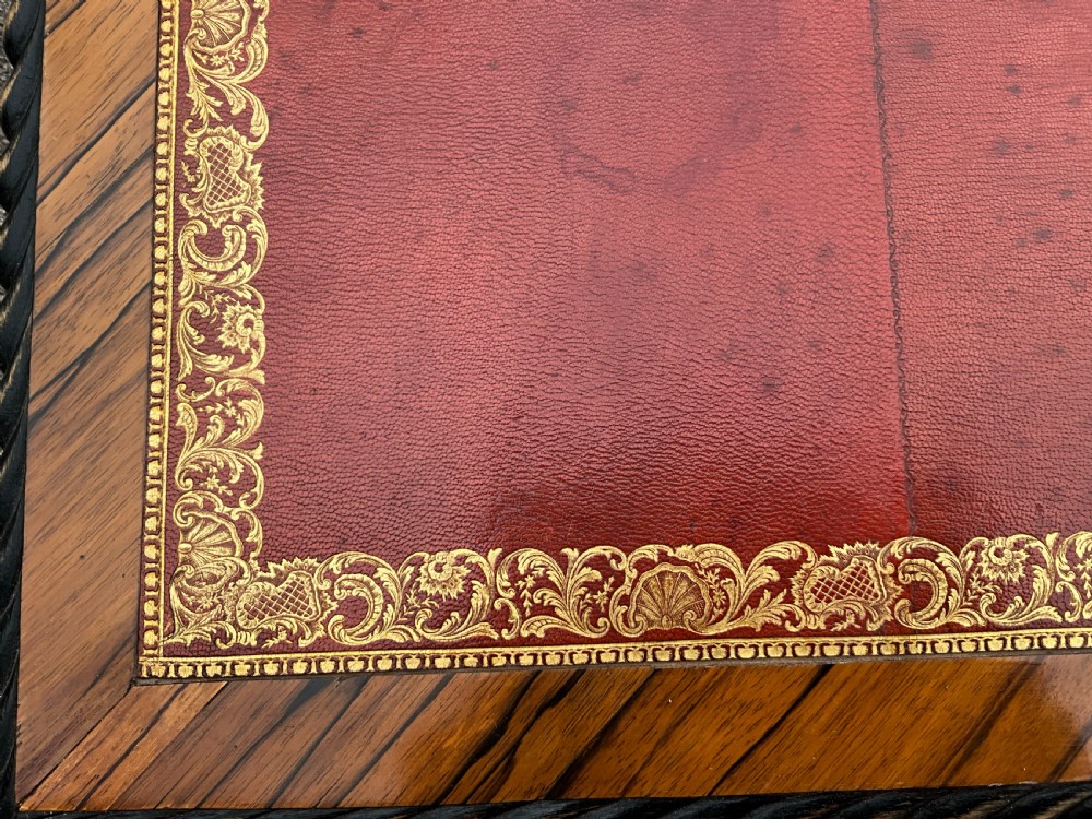 A French zebrawood writing table featuring a red leather top with gilt tooling, curved cabriole legs, and ornate gold-coloured mounts. View III