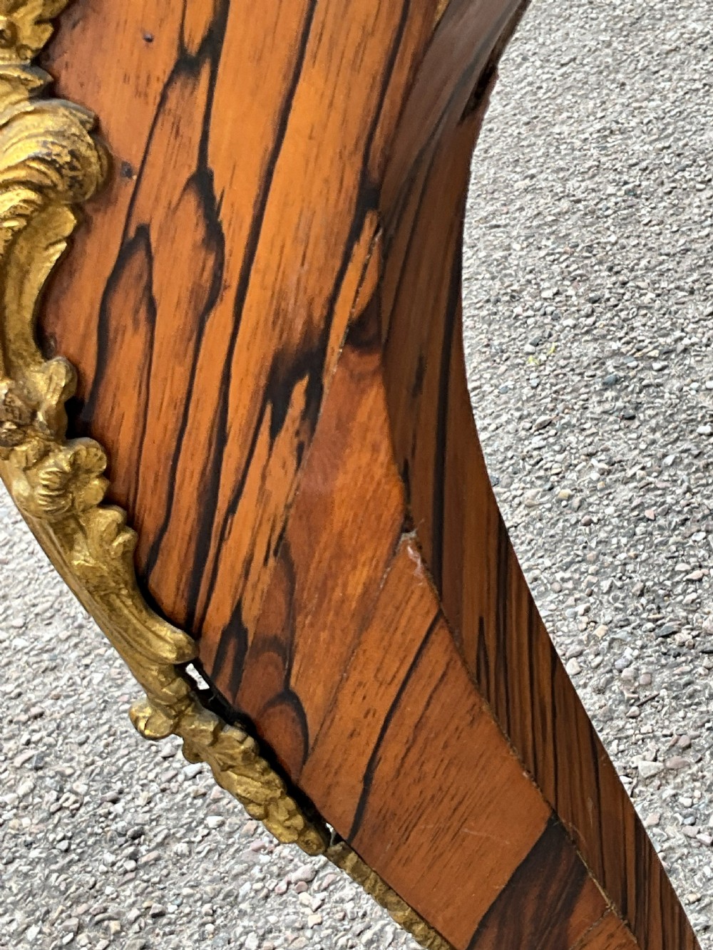 A French zebrawood writing table featuring a red leather top with gilt tooling, curved cabriole legs, and ornate gold-coloured mounts. View VII