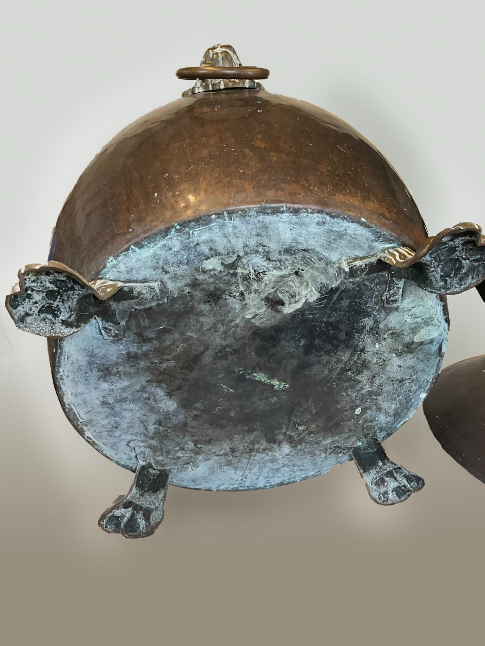 An antique dark copper cauldron featuring a domed lid, top handle, brass lion head mask ring handles, and cast feet. View IV