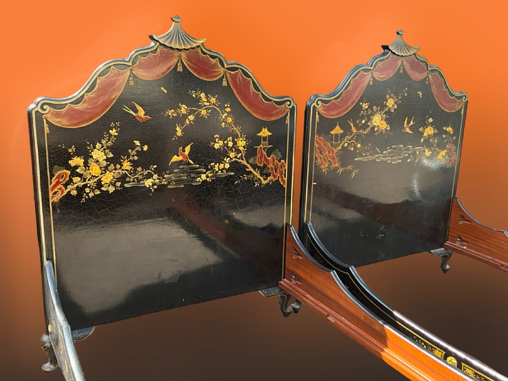 A pair of black lacquered single bed frames decorated with gold painted East Asian landscape scenes, figures, and shaped pagoda headboards. View II