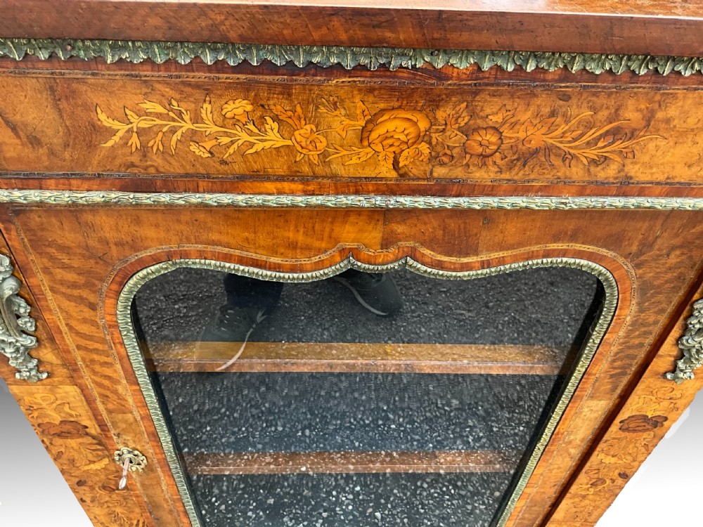 A Victorian burr walnut glazed cabinet featuring floral marquetry inlays, metal mounts, and a single glass door. View III