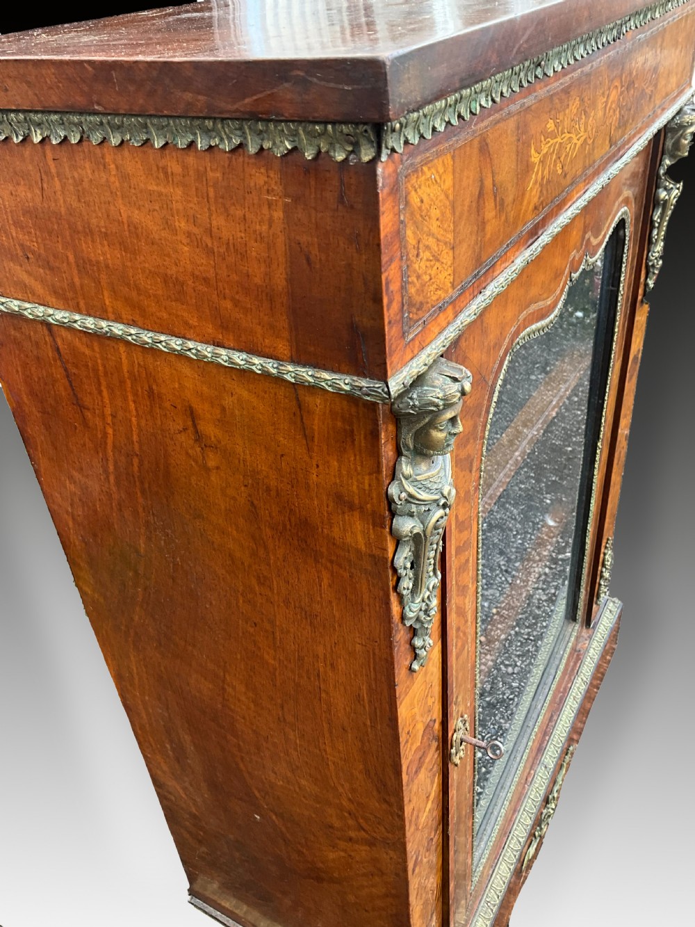 A Victorian burr walnut glazed cabinet featuring floral marquetry inlays, metal mounts, and a single glass door. View V