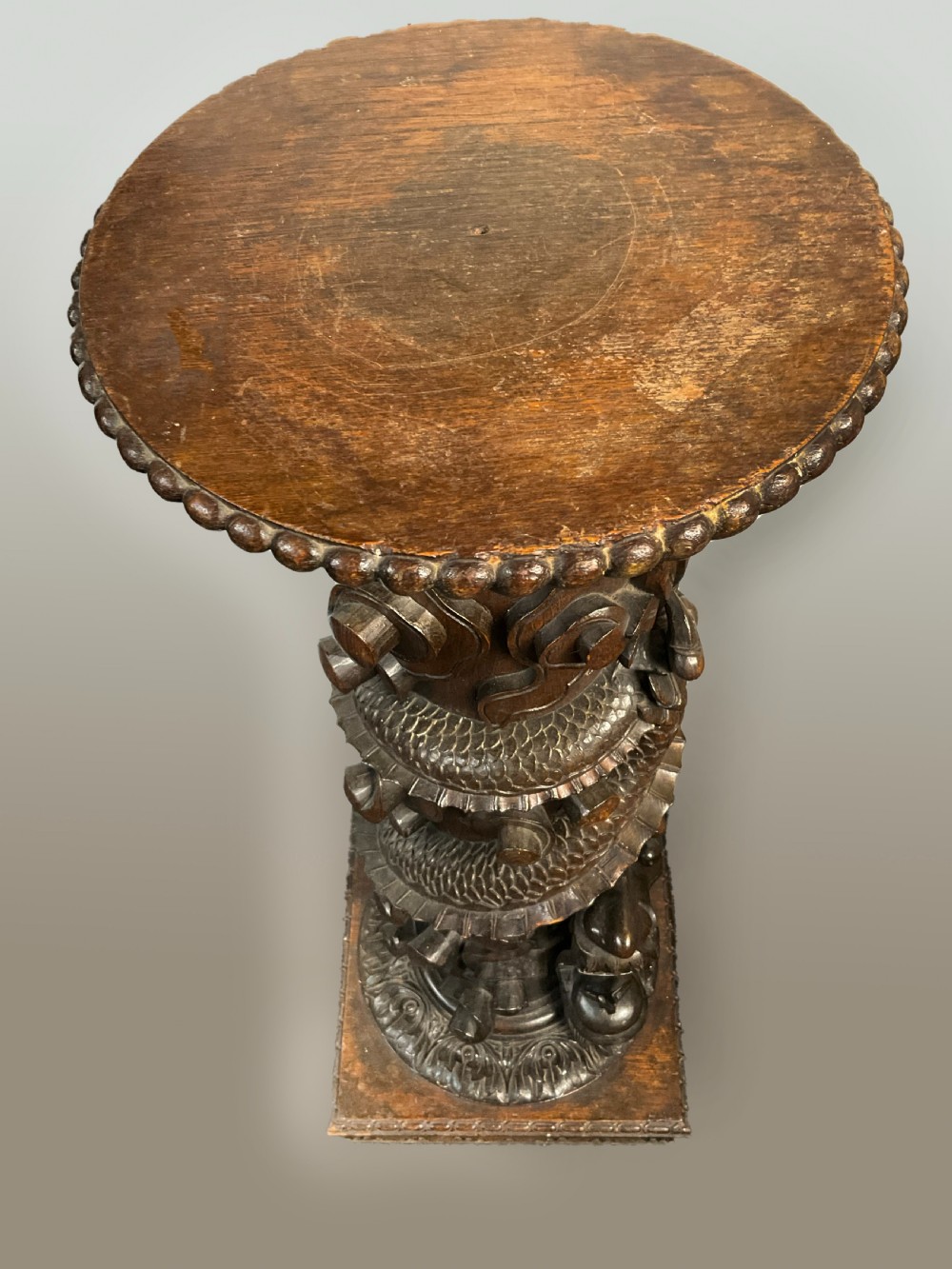 A tall dark brown hand-carved wooden column stand depicting a coiled dragon wrapped around the central shaft above a patterned square base. View IV