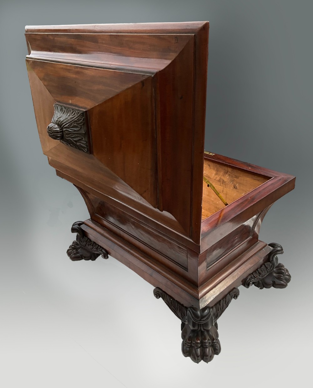 A Georgian mahogany sarcophagus wine cooler featuring a stepped lid with a carved acanthus finial and resting on four carved lion paw feet. View II