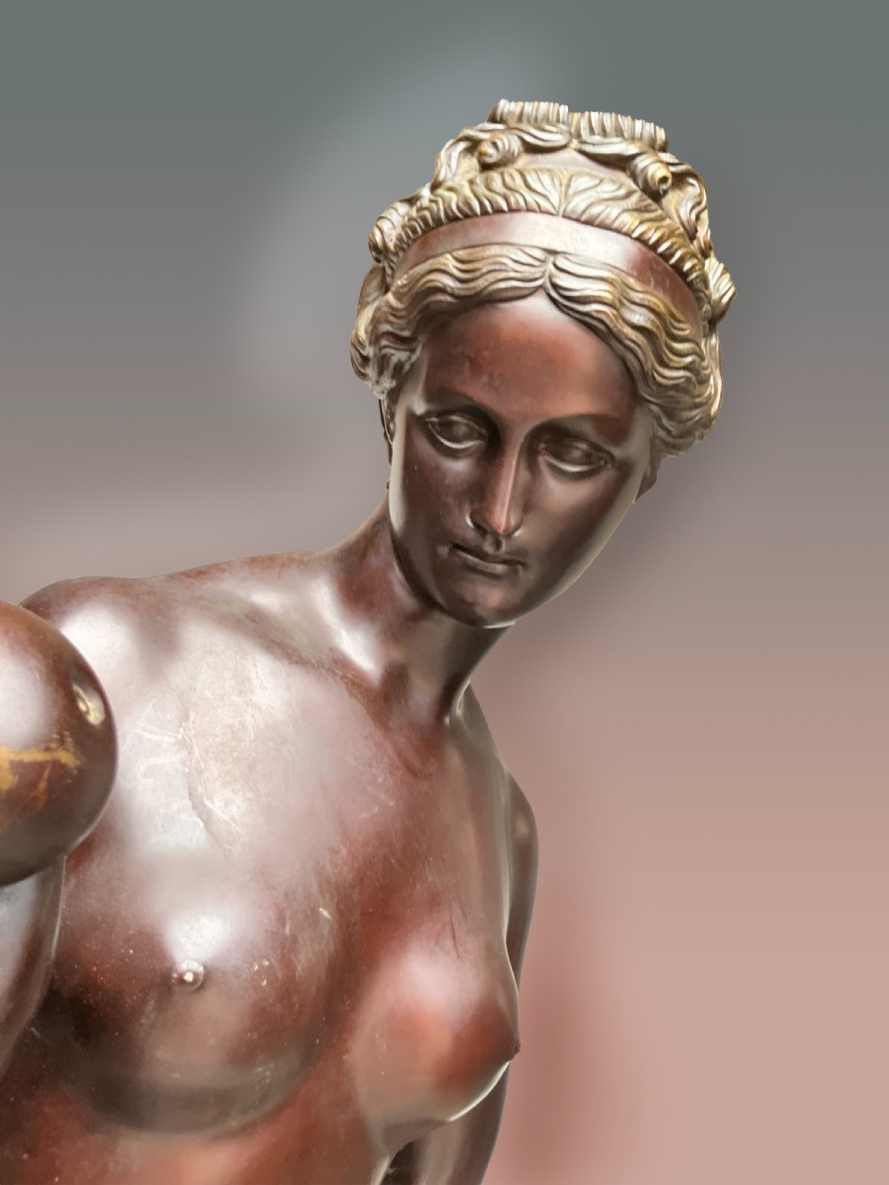 A classical bronze sculpture of a standing female figure holding a small sphere beside draped fabric on a marble base. View III